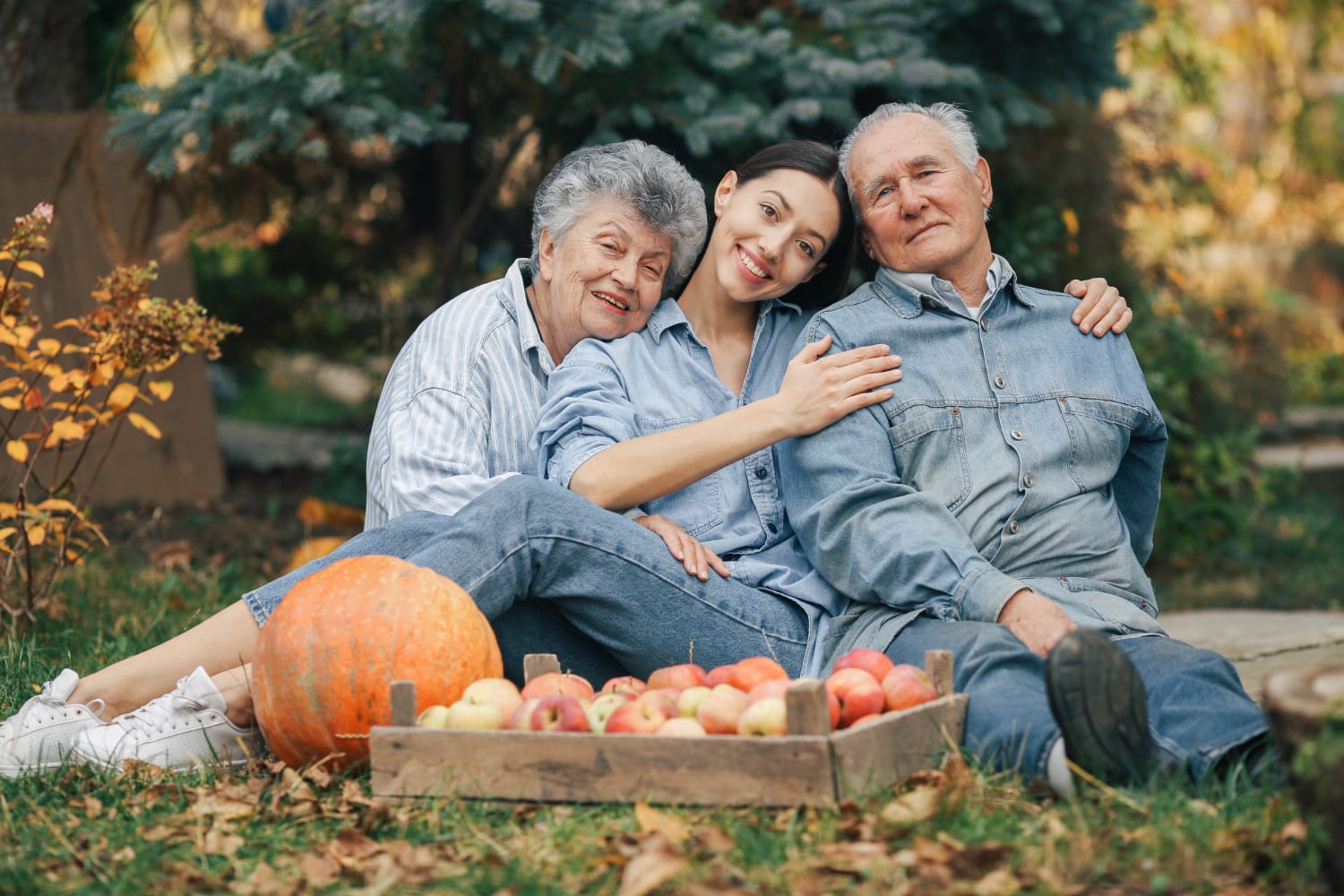 A young woman sits between her grandparents outdoors, smiling.