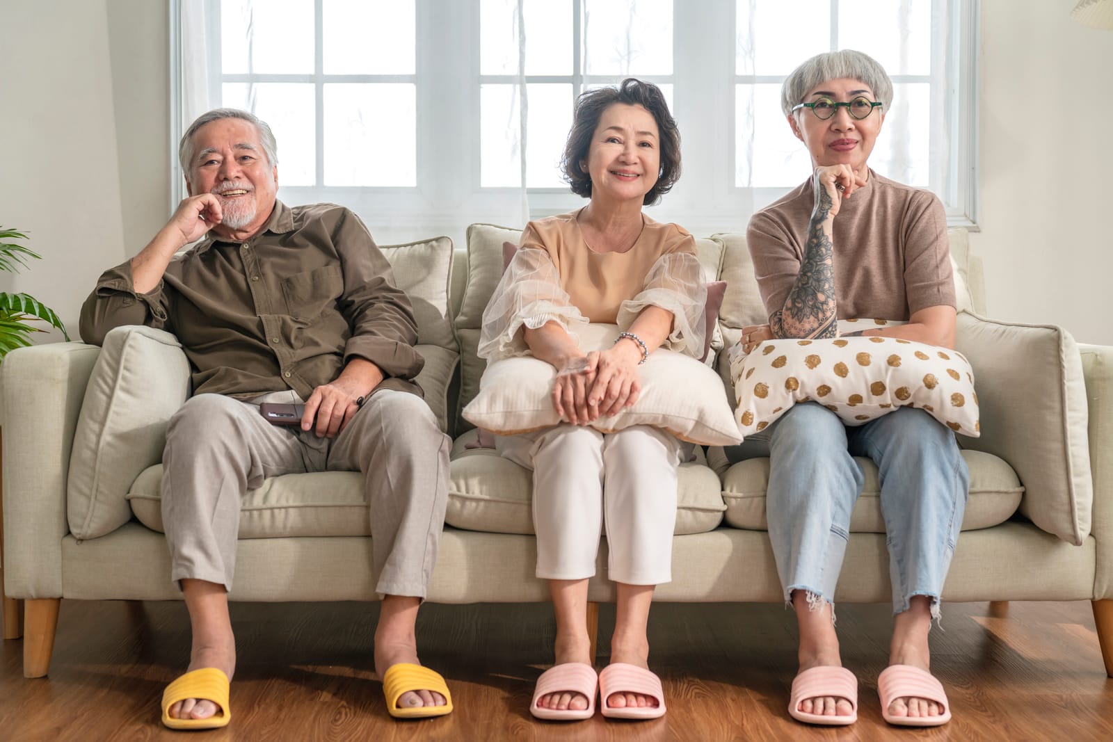 Group of asian old senior male and female spending weekend time together sit on sofa couch watching tv comedy program with joyful laugh smiling happiness expressionsenior people in nursing home