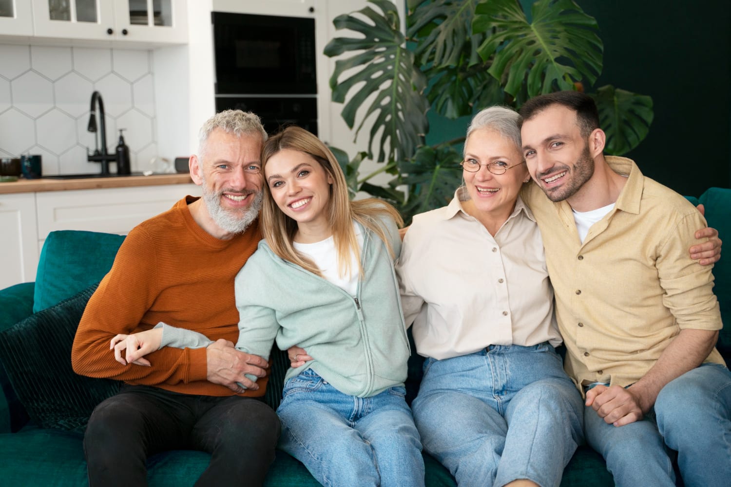 A family of four sitting closely together on a couch, smiling and enjoying each other's company in a cozy living room.