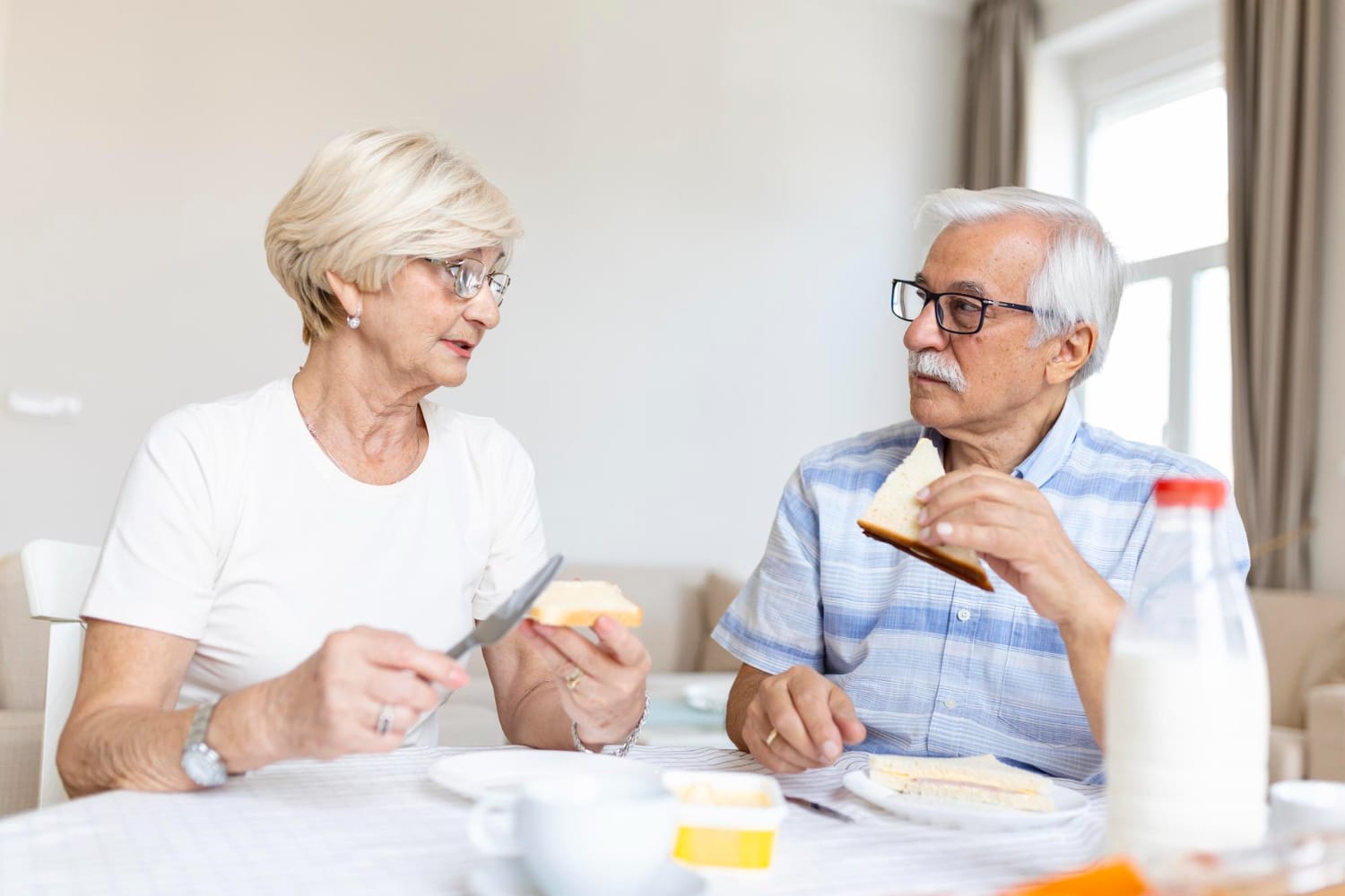An older couple enjoying breakfast together, smiling and sharing a moment over their meal.