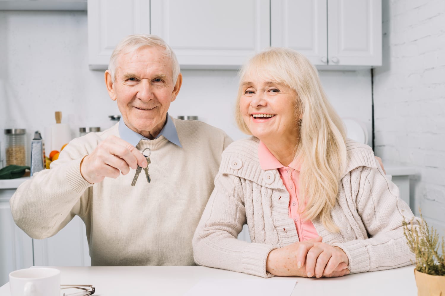 Happy elderly couple with keys in hand, representing a milestone or new beginning in their lives.