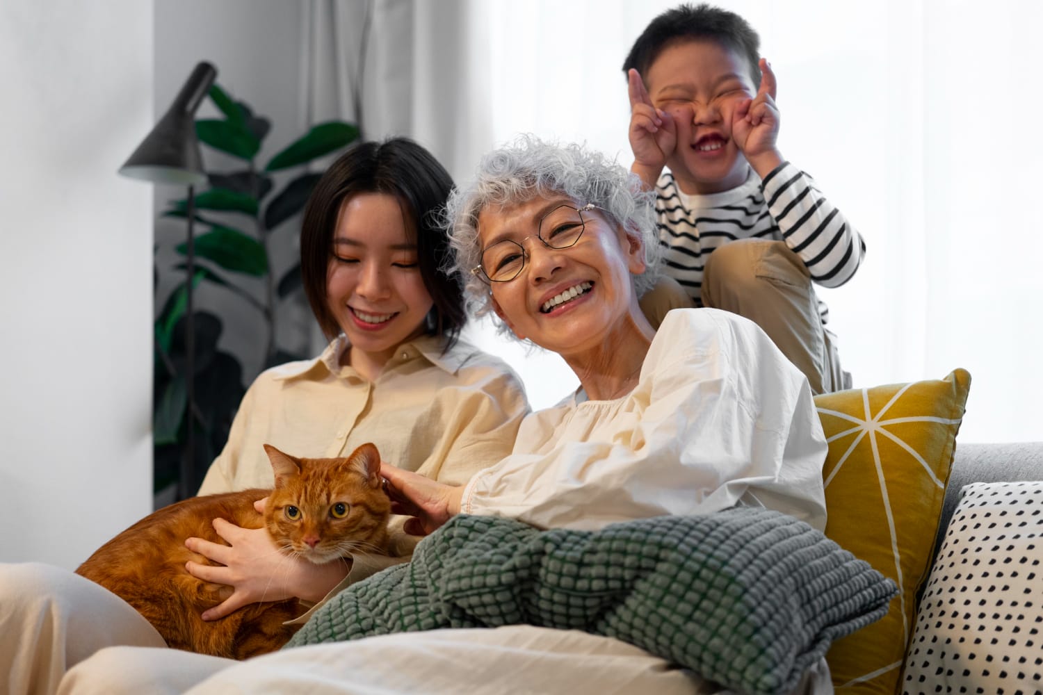 An Asian woman and her family, including a playful cat, enjoying a moment together at home.