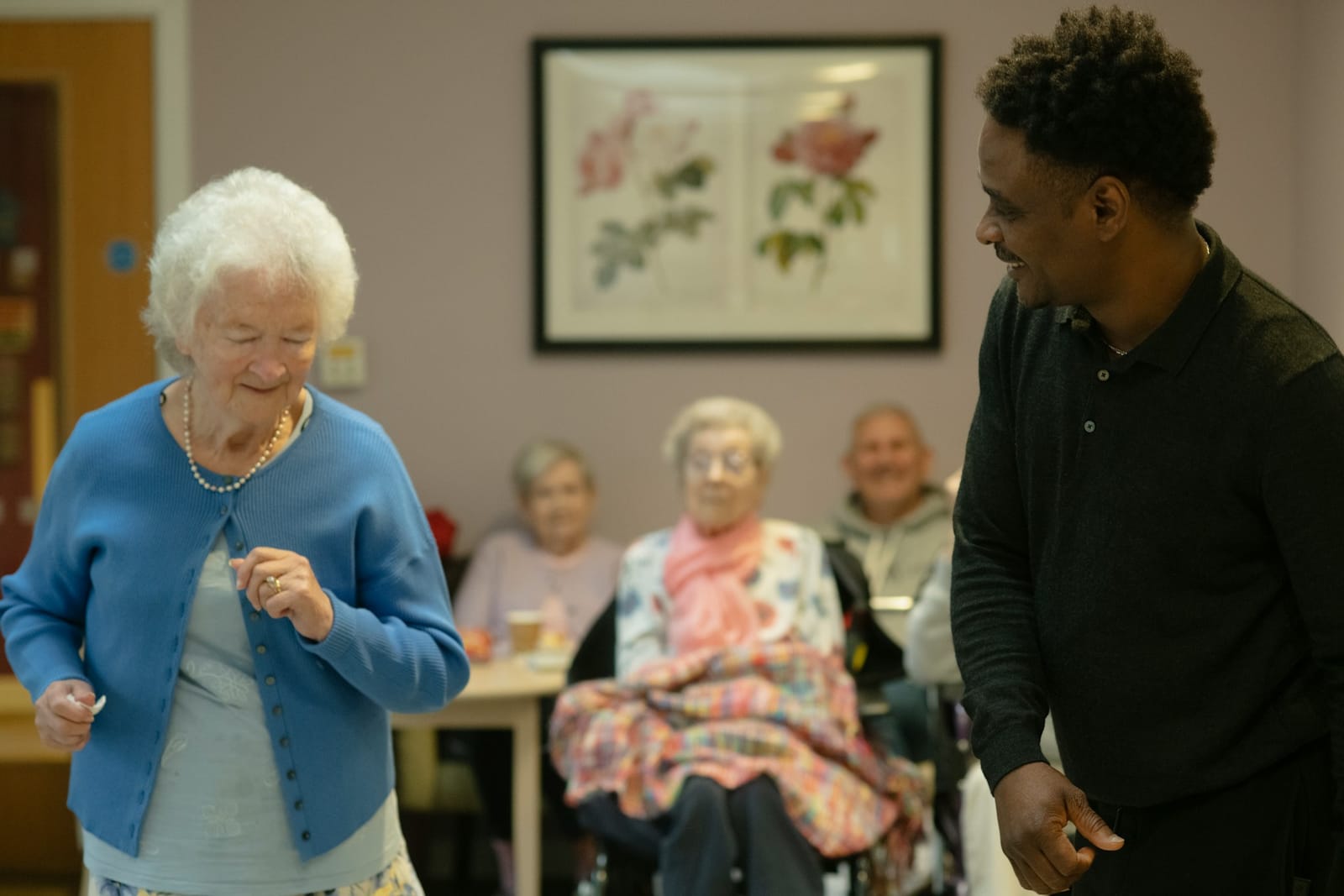A man and woman joyfully dancing together in a nursing home, surrounded by a warm and inviting atmosphere.
