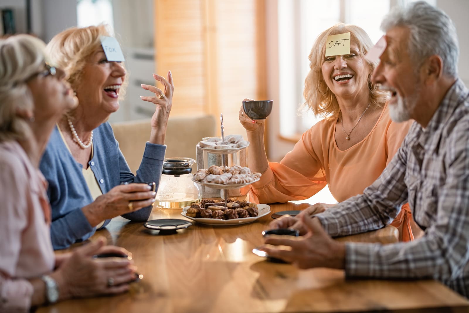 Active senior residents laughing over coffee and games at The Berkeley at Short Pump