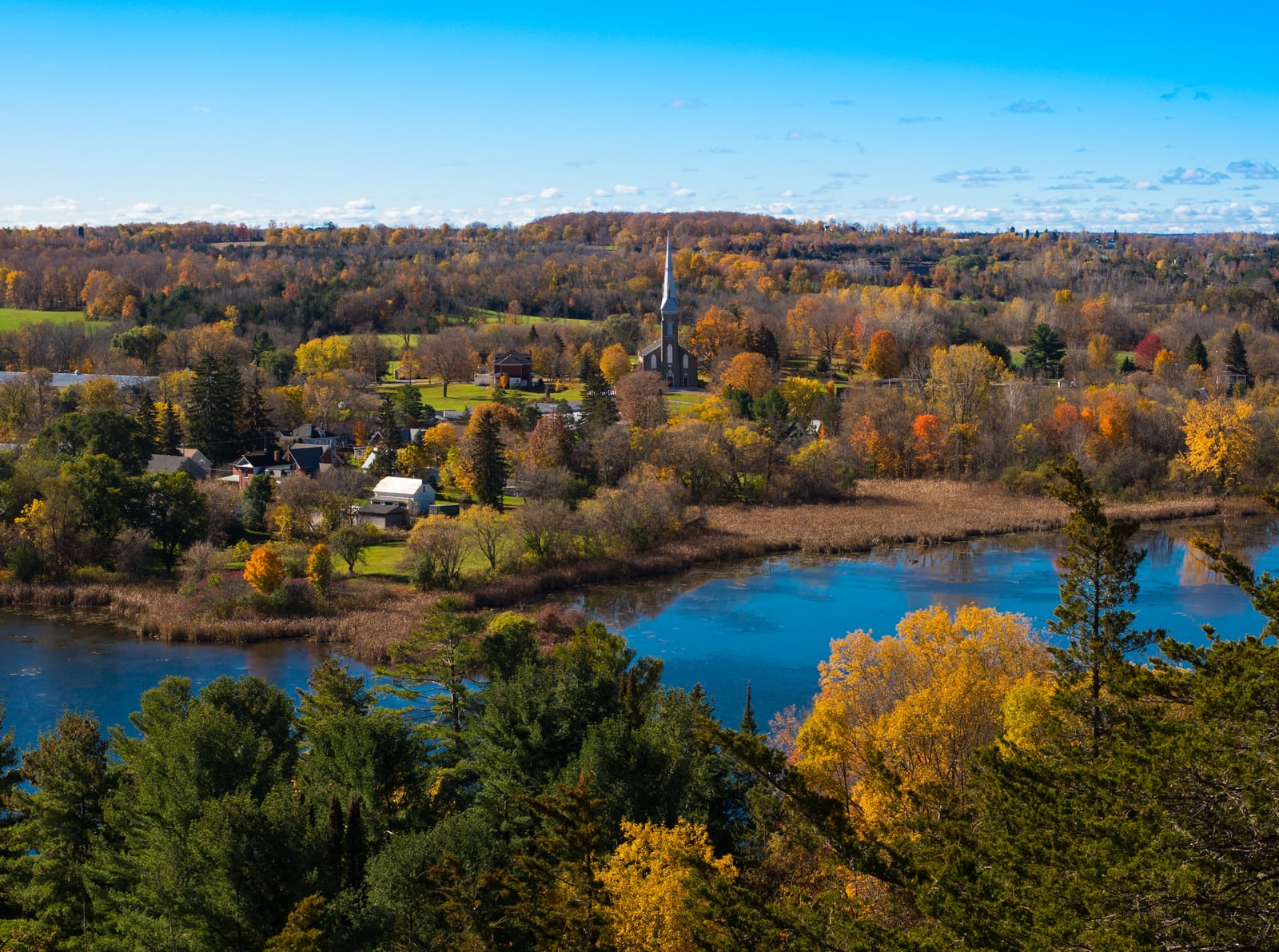 An autumn view over a small town nestled among colorful trees and a winding river